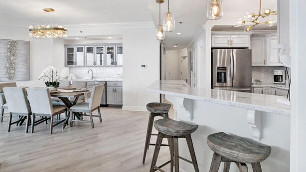 A modern kitchen with white cabinets, a stainless steel refrigerator, and pendant lighting. - Serenity Awaits: Unwind in Style with Our Premier Orange Beach Condo Rental (Orange Beach)