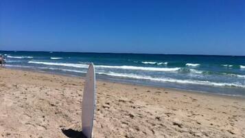 Una playa con una tabla de surf apoyada en la arena.
