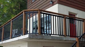 Un edificio de dos pisos con un balcón, una puerta roja y una escalera.