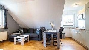 En moderne lejlighed med spiseplads, sofa og køkken.