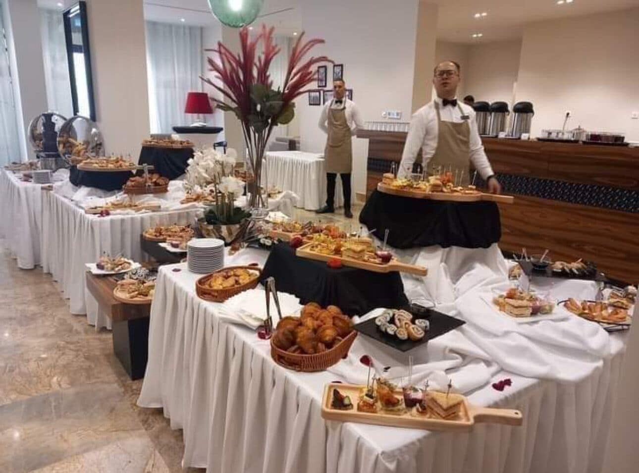 A buffet setup with various food items and a waiter.