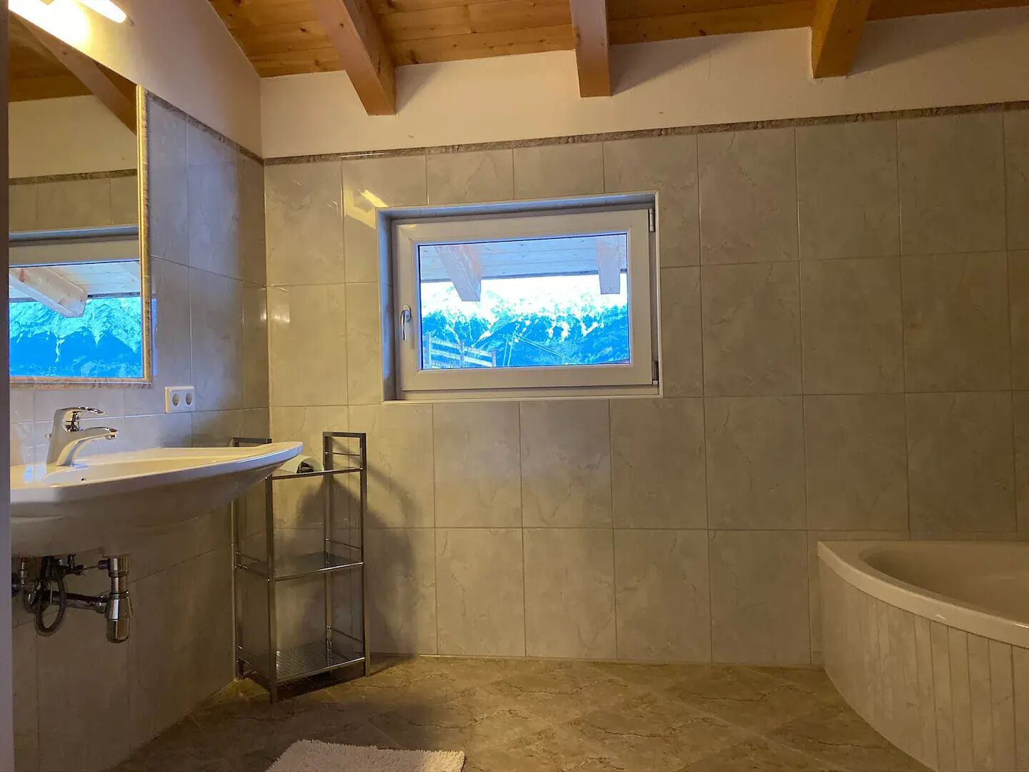 A bathroom with a bathtub, a sink, and a window with a view of trees.