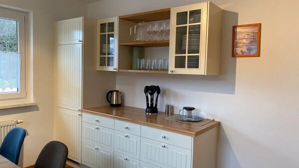 Una cocina con armarios blancos, encimera de madera y ventana con vistas.