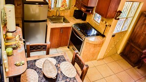Una cocina compacta con refrigerador, estufa, lavamanos y armarios de madera.