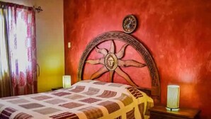 Una habitación con una cama, cabecera de madera, mesita de noche y un reloj de pared.