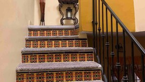 Una escalera con baldosas de colores y diseños, un reloj de pared y un farol decorativo.