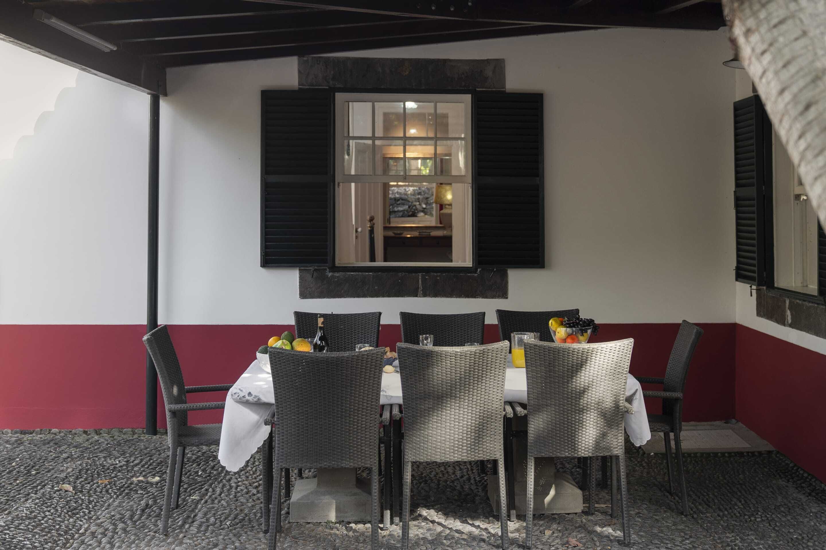 Un espace extérieur aménagé pour les repas, avec une table dressée pour six personnes, entourée de chaises en osier.