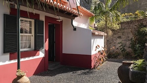 A building with a red and white facade, a tiled roof, and a gravel pathway leading to the entrance. - On the North Coast, by the sea - Casa do Terreiro (São Vicente)