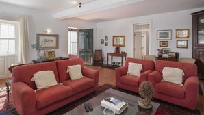 A living room with two red sofas, a coffee table, and a small decorative tree. - On the North Coast, by the sea - Casa do Terreiro (São Vicente)