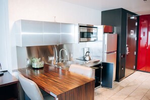 Una cocina moderna con electrodomésticos de acero inoxidable, una encimera de madera y un armario rojo.