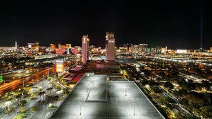 A nighttime cityscape with illuminated buildings and a prominent hotel with two towers.