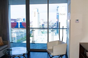 A hotel room with a glass door leading to a balcony with a city view, a white chair, and a small table. - Palms Place Hotel StripView (Las Vegas)