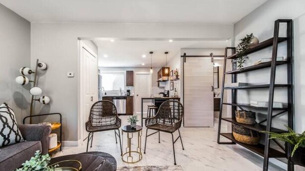 Una sala de estar moderna con un sofá, dos sillones de mimbre, una mesita de centro y una estantería.