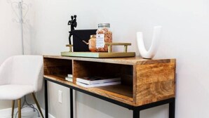 Una consola de madera con un tarro de frutos secos, un libro y un florero blanco.
