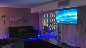 Olohuoneessa on sohva, rahi ja seinälle asennettu taulutelevisio.
