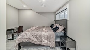 Un dormitorio moderno con cama, escritorio, silla y ventana.