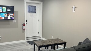 Una sala de estar moderna con un sofá gris, una mesa de centro y un televisor de pantalla plana montado en la pared.