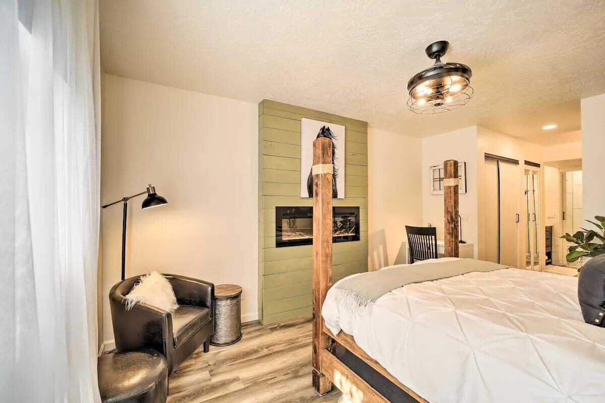 A bedroom with a bed, a chair, a desk, a lamp, and a wall-mounted shelf.