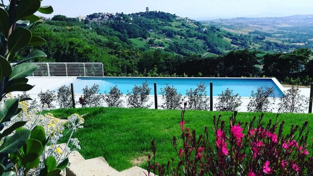Una piscina con vistas a una colina verde y un pueblo lejano.