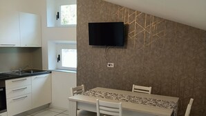 Una cocina moderna con armarios blancos, encimera negra y un comedor con mesa y sillas.