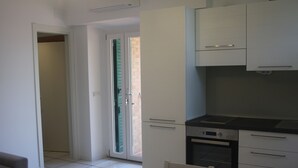 Una cocina moderna con armarios blancos, horno integrado y comedor con mesa y sillas.