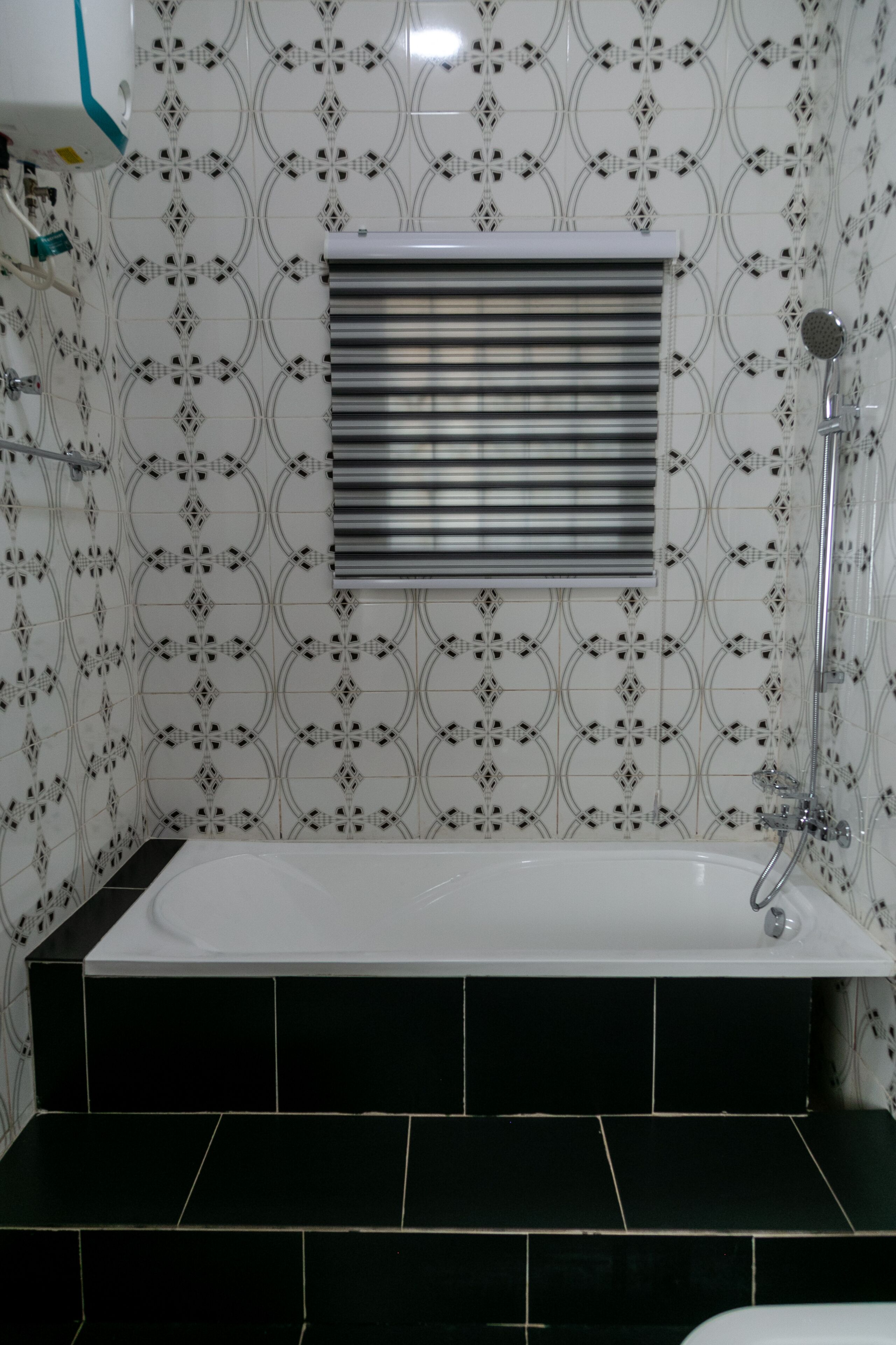 Een badkamer met een wit bad, zwarte tegels en een behangen muur.