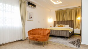 A modern bedroom with a bed, a chair, and a nightstand. - Sunrise Cave Guest House (Oyibi)