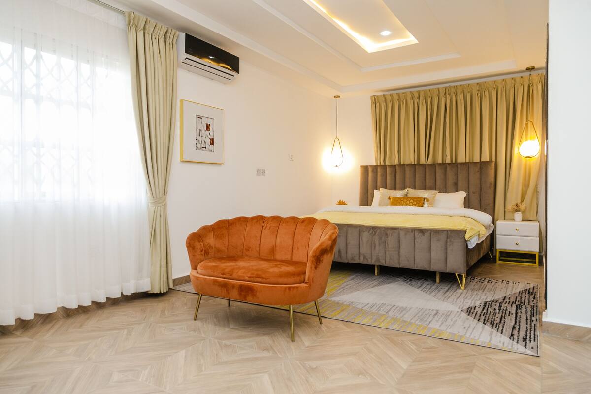 A modern bedroom with a bed, a chair, and a nightstand.