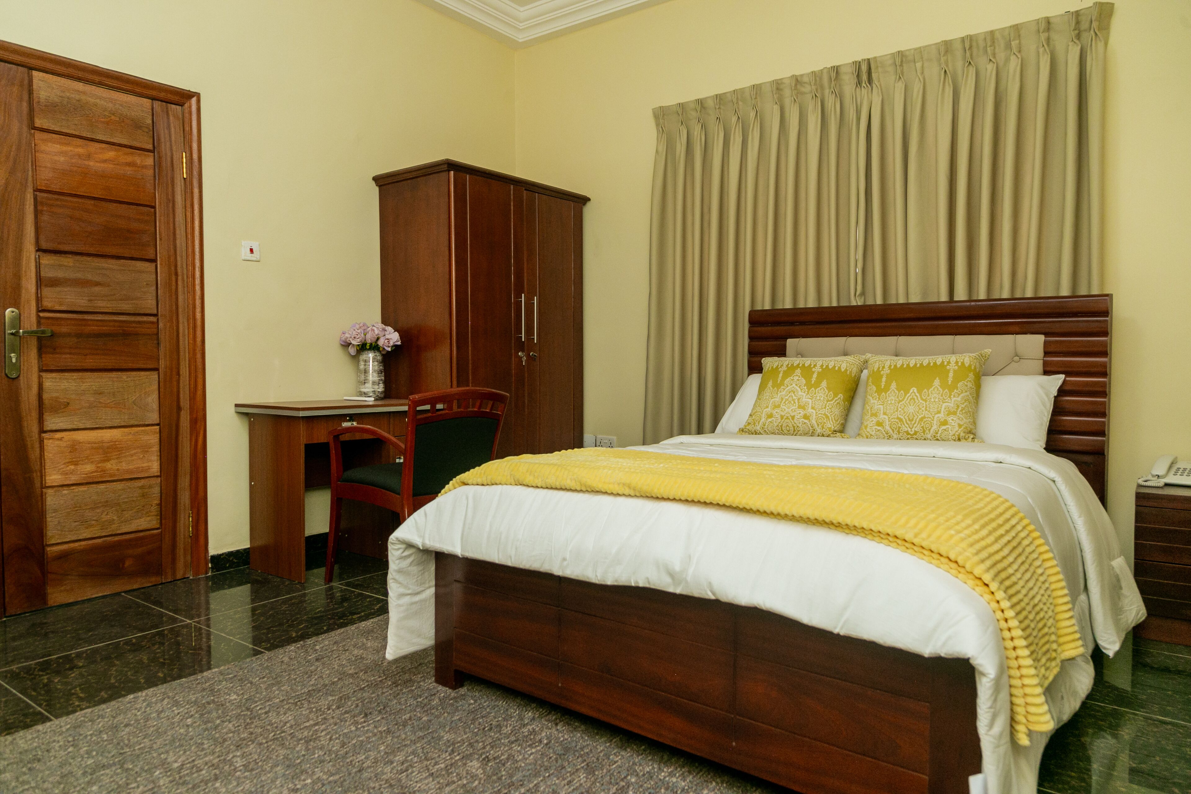 A bedroom with a wooden bed, a desk, a chair, and a wardrobe.