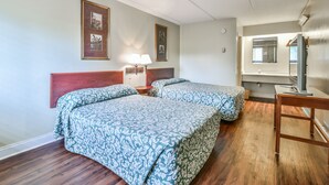 Hotelkamer met twee bedden, een houten hoofdeinde, nachtkastjes met lampen, een spiegel en een houten bureau.