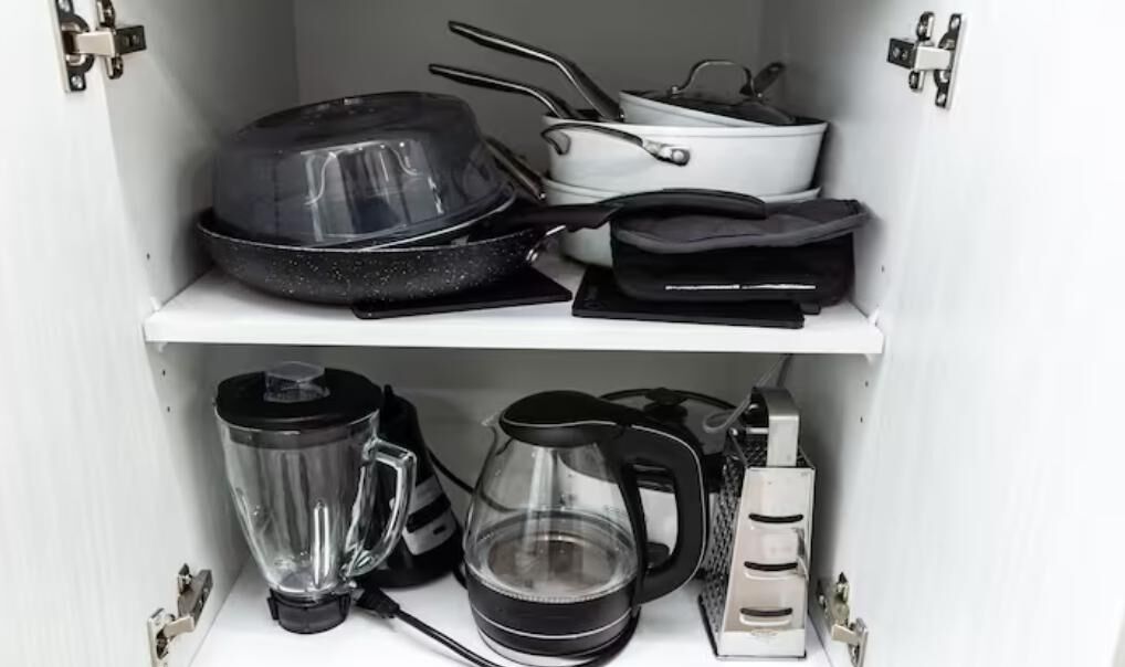 Eine Küche mit Mixer, Wasserkocher und Töpfen auf Regalen.