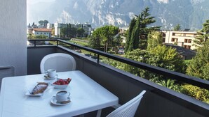 Un balcon avec une table préparée pour le petit-déjeuner, offrant une vue sur un paysage montagneux.