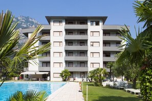 Un hôtel à plusieurs étages doté d’une piscine, d’un espace extérieur aménagé et offrant une vue sur les montagnes.