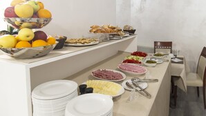 Un buffet proposant une variété de plats, notamment des fruits, des pâtisseries et des produits de la charcuterie.
