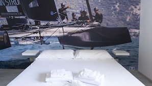 Un lit avec du linge de lit blanc et des oreillers, une serviette soigneusement pliée et un arrangement floral.
