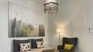 Un soggiorno moderno con un divano, una poltrona verde, un tavolino rotondo, una lampada da terra e un grande quadro astratto appeso al muro.