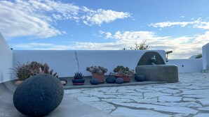 Una terrazza sul tetto con piante in vaso, pavimento in pietra e parete bianca.
