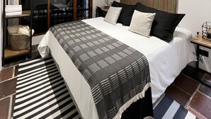 A bedroom with a bed, a window, an air conditioning unit, and a patterned rug. - Casa Medallo (Medellín)