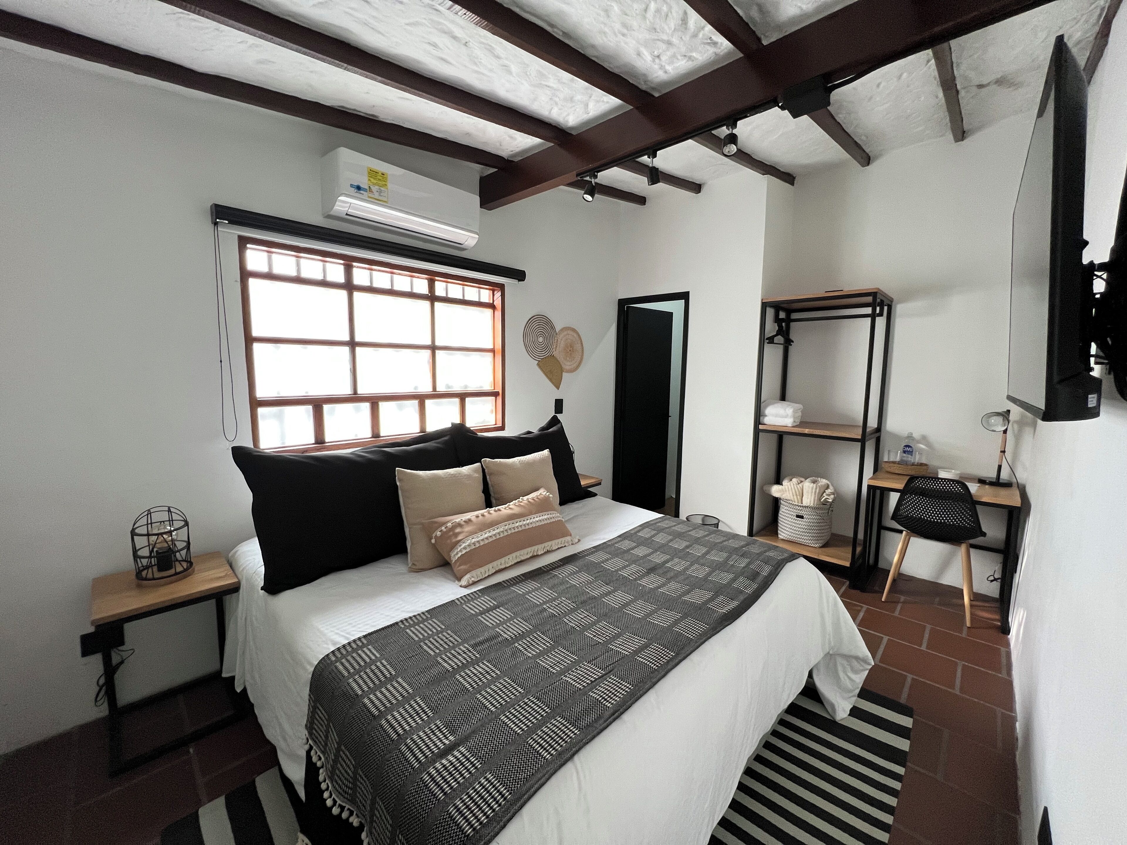 Un dormitorio con cama, ventana, armario, escritorio y silla.