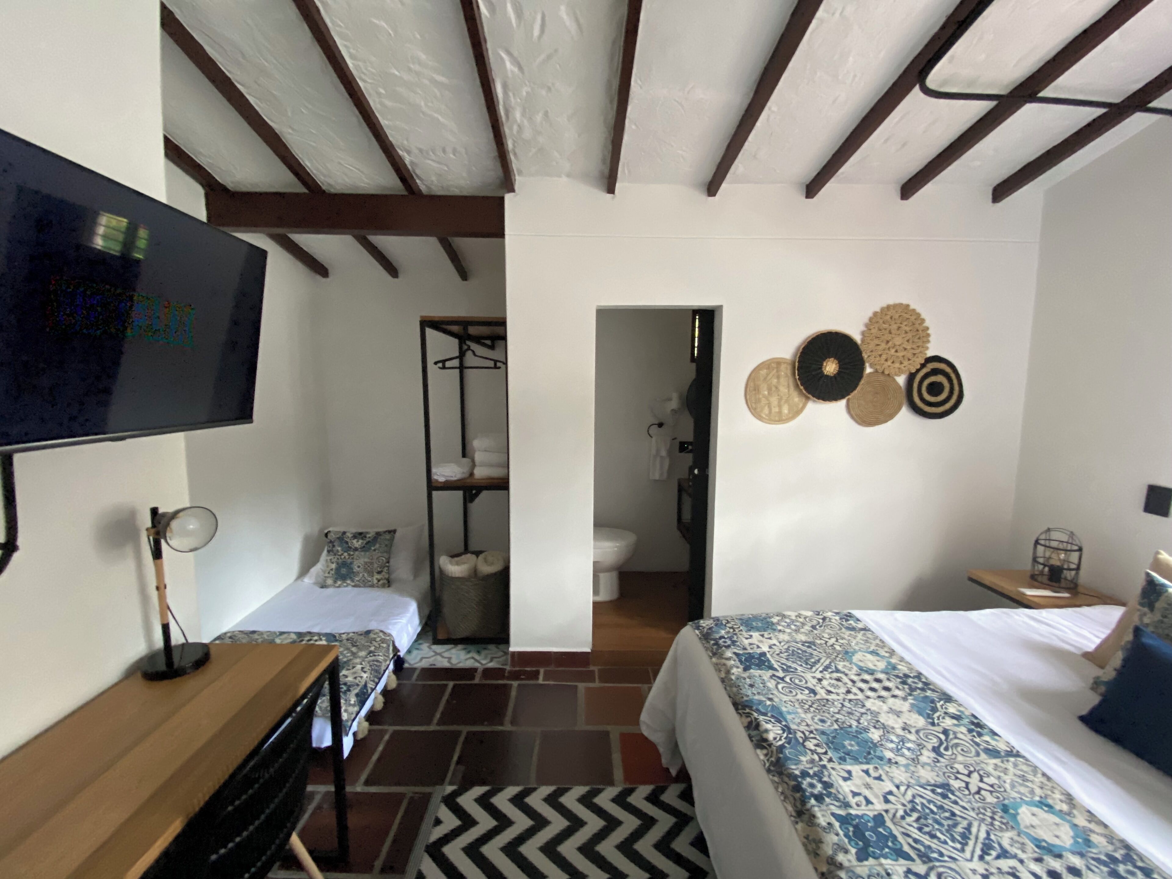 Habitación de hotel con cama, televisión, escritorio y armario.
