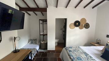 Habitación de hotel con cama, televisión, escritorio y armario.