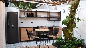 A compact kitchen with a refrigerator, microwave, and sink. There is a small dining area with a table and chairs. - Casa Medallo (Medellín)
