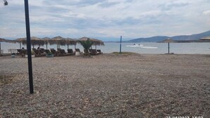 A beach with sun loungers and umbrellas, a clear sky, and calm water. - Άνετο παραθαλάσσιο διαμέρισμα με υδρομασάζ , δέκα λεπτά  από τους Δελφούς ! (Itea)