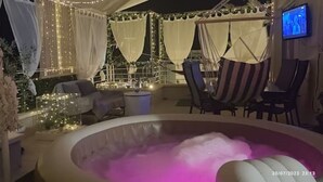 An outdoor hot tub area with a pool, surrounded by string lights and white drapes. - Άνετο παραθαλάσσιο διαμέρισμα με υδρομασάζ , δέκα λεπτά  από τους Δελφούς ! (Itea)