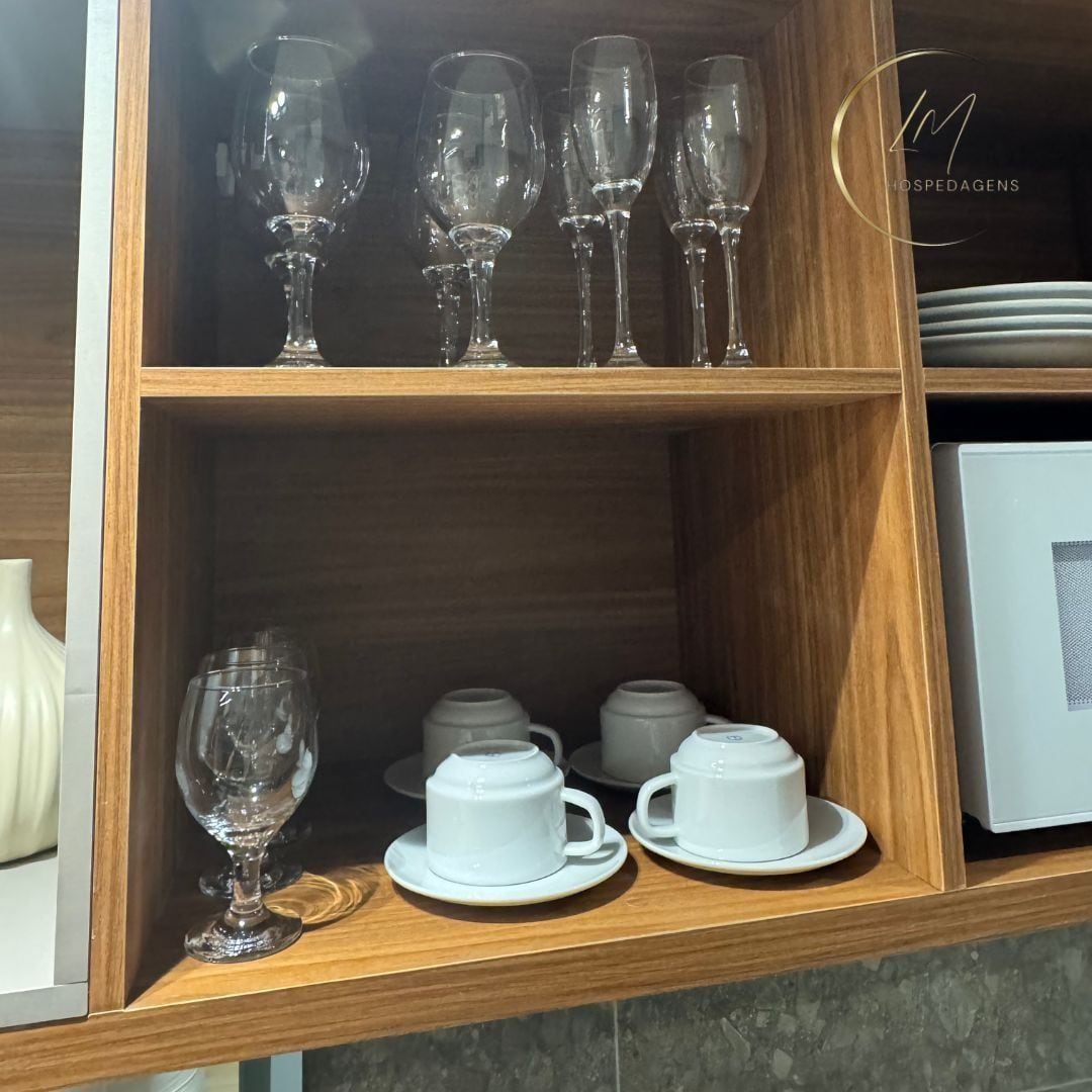 A wooden shelf with various glassware and white ceramic cups.
