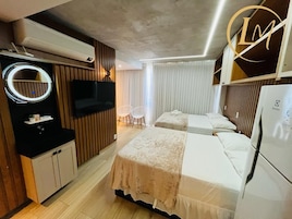 Quarto de hotel com duas camas, televisão, frigobar e geladeira.