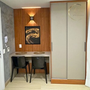Una habitación con panel de madera en la pared, una obra de arte enmarcada, un escritorio con dos sillas y un armario con un logotipo circular.