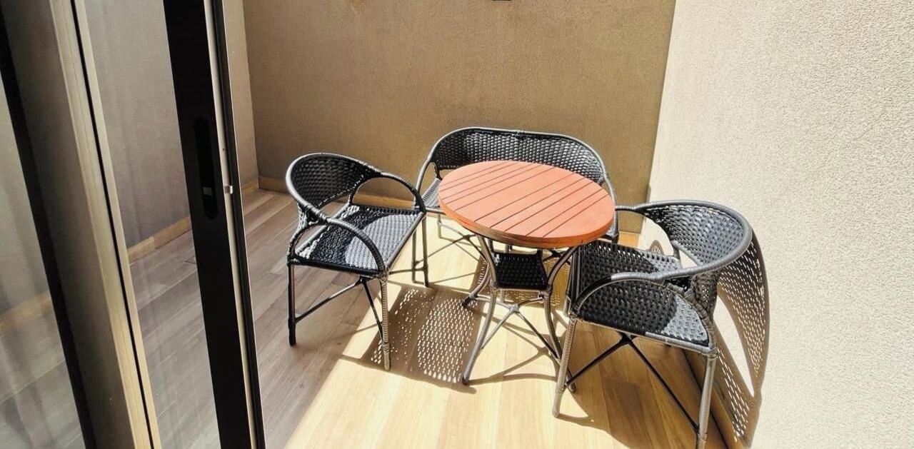 Un pequeño espacio al aire libre con una mesa redonda y cuatro sillas.