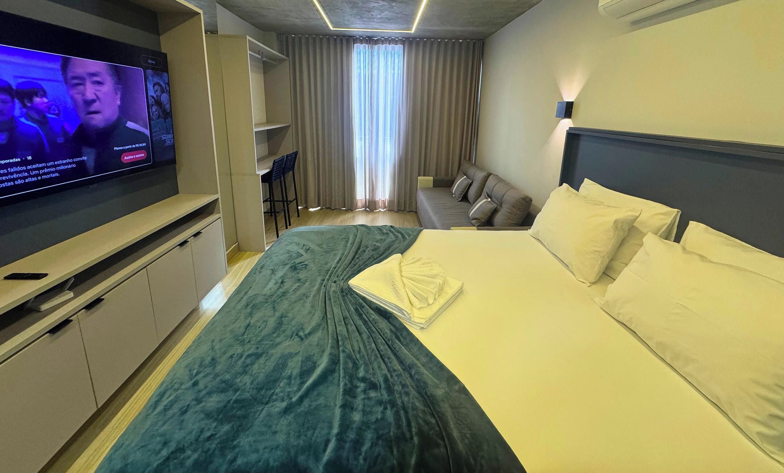 Una habitación de hotel con una cama, un televisor, un escritorio y una silla.