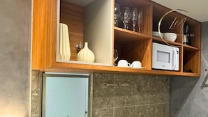 Une cuisine compacte dotée d’un four à micro-ondes encastré, d’un évier et d’armoires en bois.